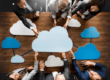 computer image of a cloud with an arrow in it pointing up||people in a board room sitting on either side of a table with cloud icons in the middle