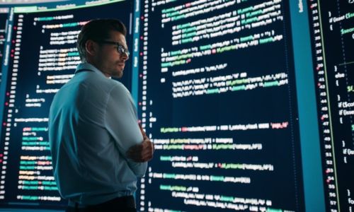 man standing in front of large screen reading code