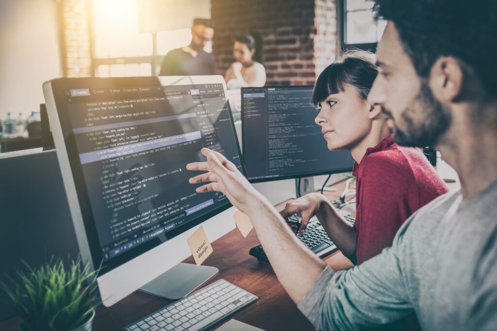 two people sitting next to each other at a computer monitor